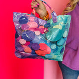 Glossy tote bag with colorful confetti print in turquoise, pink, purple, coral, and blue