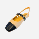 Two tone slingback flats with cream body, black cap toe, and grommet strap detail
