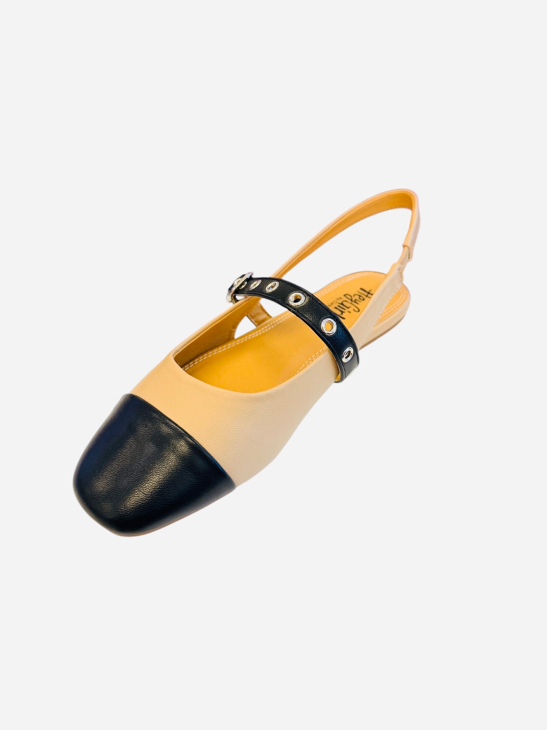 Two tone slingback flats with cream body, black cap toe, and grommet strap detail