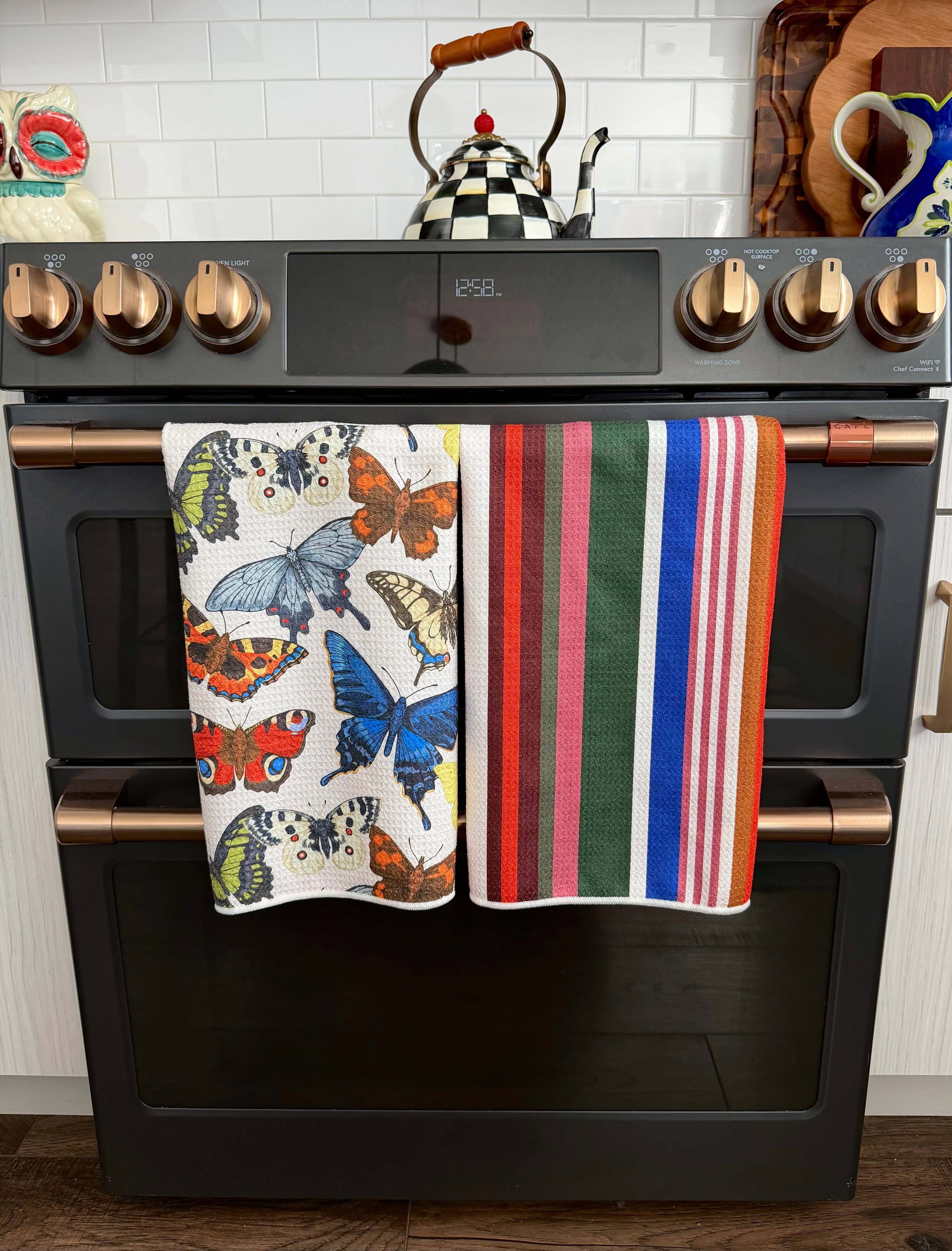 Two Crae hand towels with colorful butterfly and multicolor striped designs.