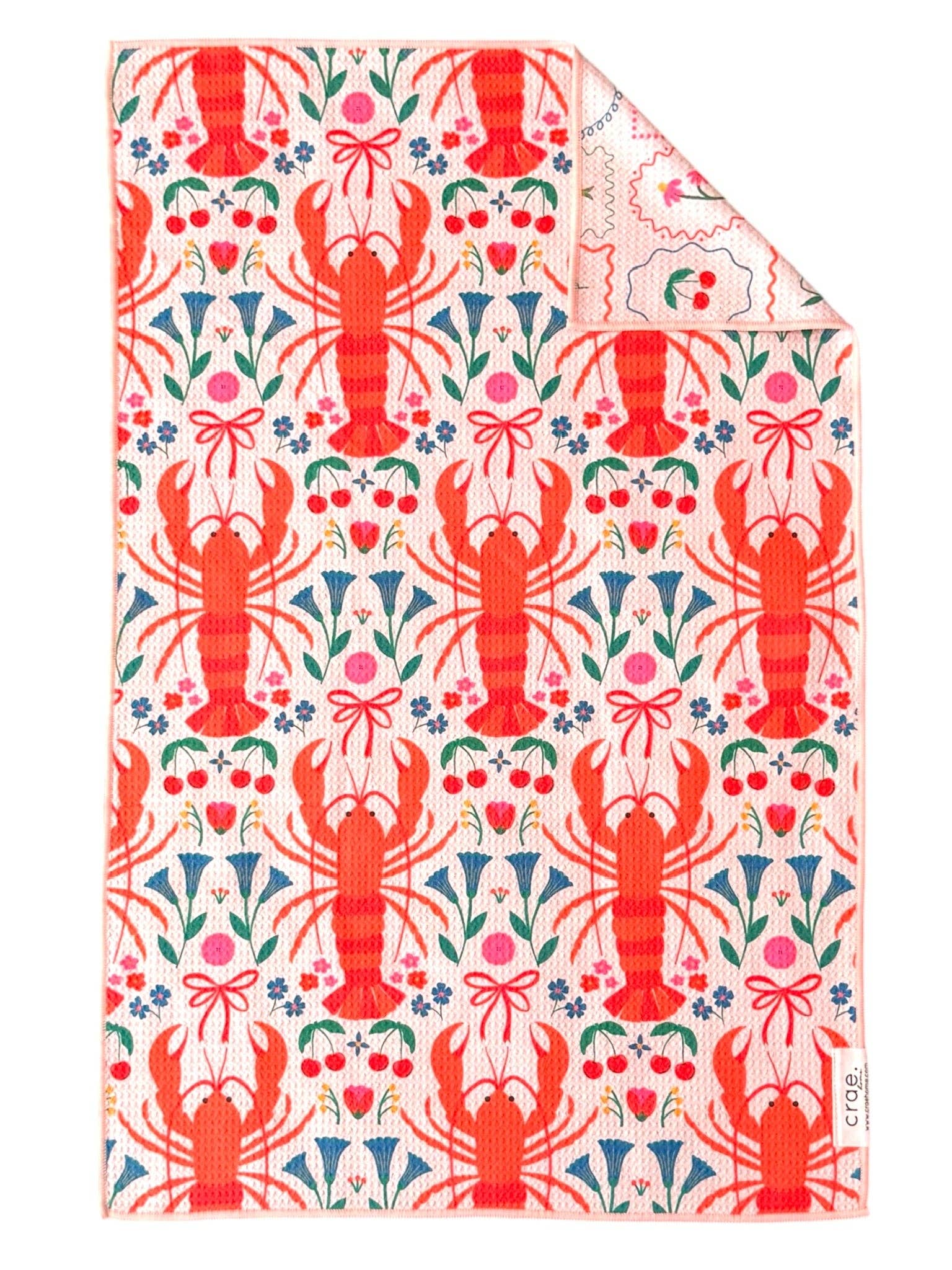Reversible Crae towel with red lobsters, colorful florals, cherries, bows, and vintage-style frames.