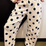 Cream barrel-leg pants with bold navy polka dots and elastic waistband.