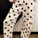 Cream barrel-leg pants with bold navy polka dots and elastic waistband.