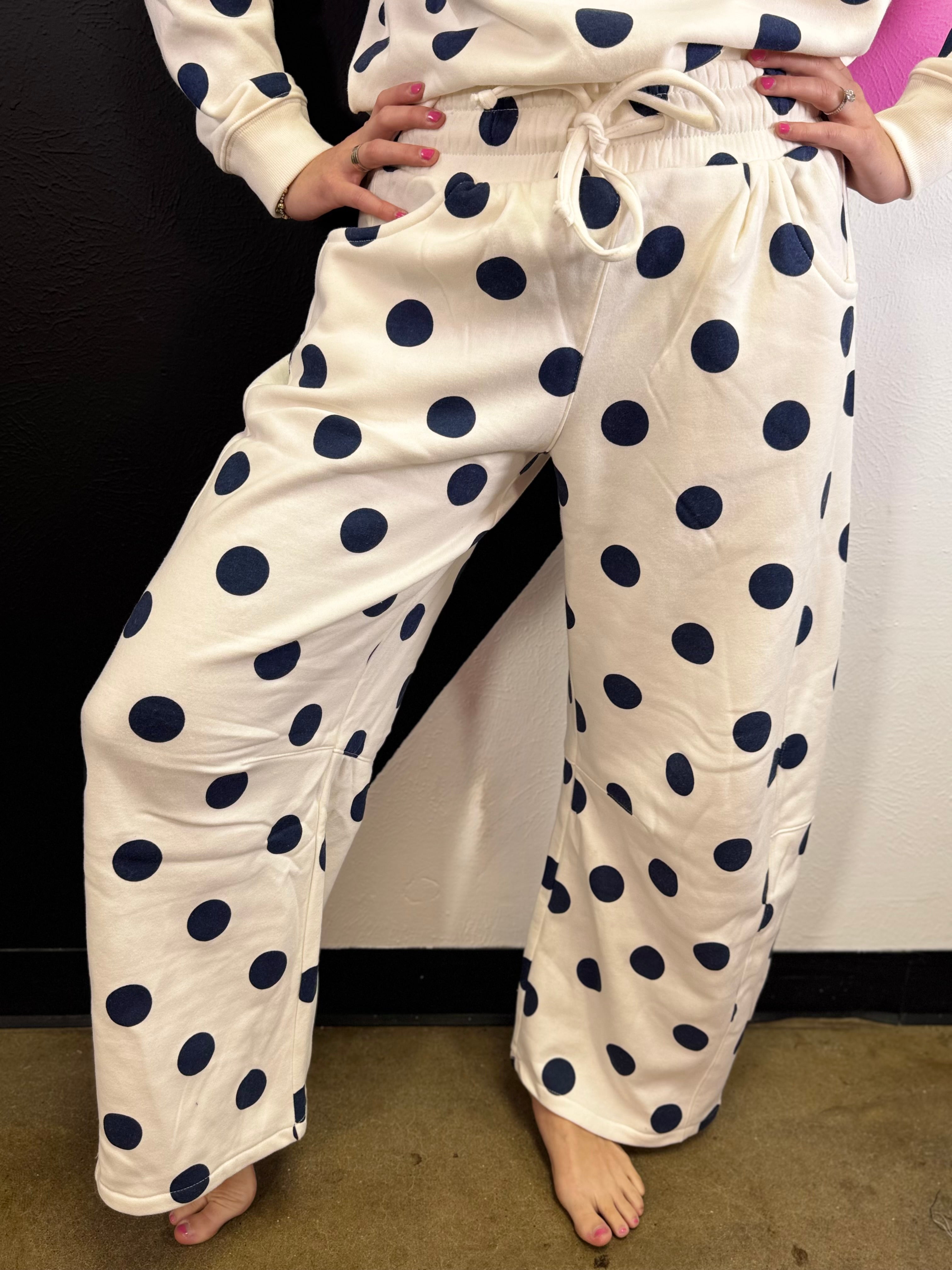 Cream barrel-leg pants with bold navy polka dots and elastic waistband.