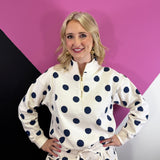 Cream quarter-zip pullover with navy polka dots, long sleeves, and ribbed cuffs and hem.