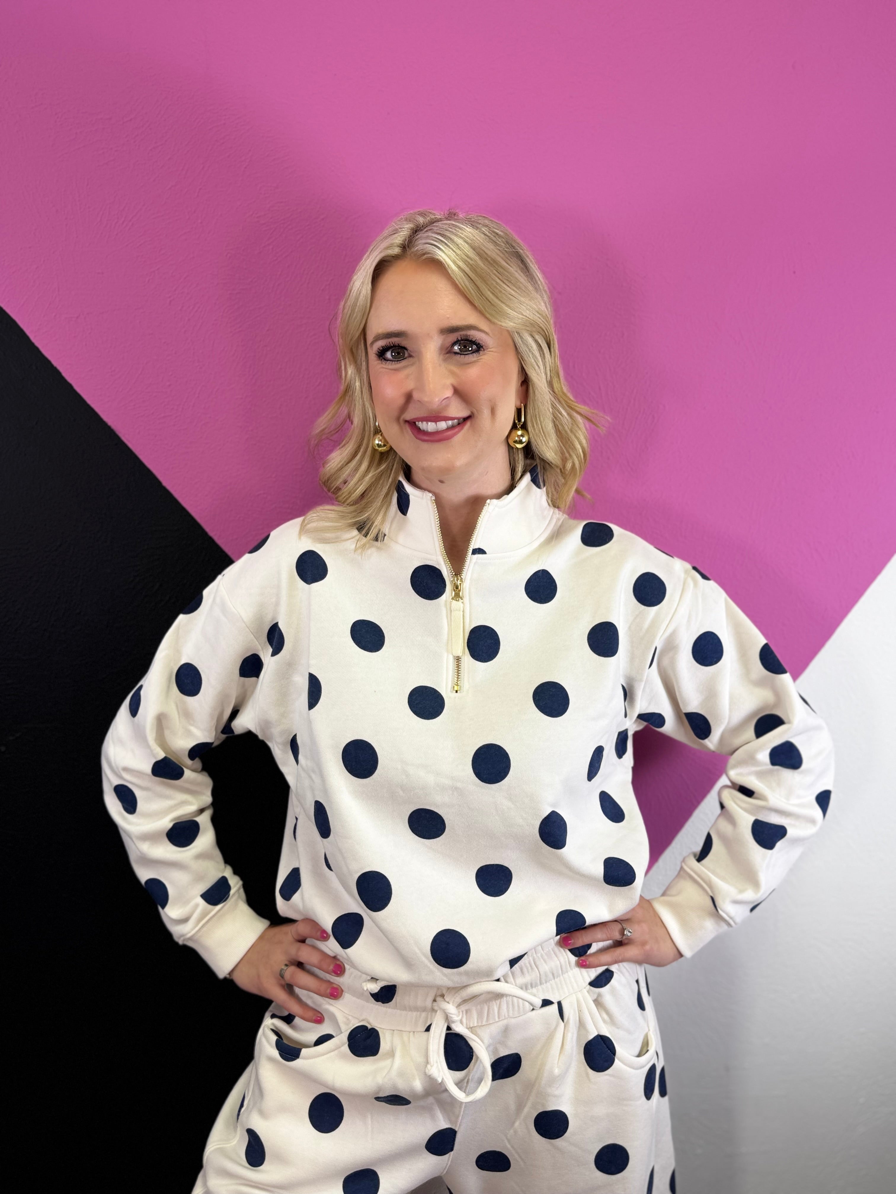 Cream quarter-zip pullover with navy polka dots, long sleeves, and ribbed cuffs and hem.