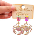 Rhinestone crab dangle earrings with gold details and oversized iridescent multicolor crystal studs.