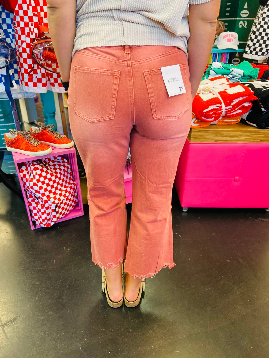 Back side of Cabernet colored jeans with cropped length and distressing at knees. Raw hem line.