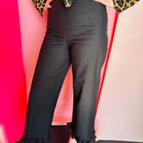 Black high-rise straight-leg pants with subtle ruffled hem and clean back zipper closure.