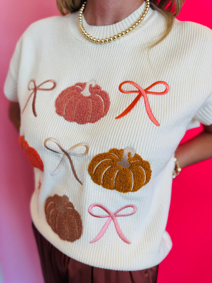 Lightweight knit sweater with rows of colorful pumpkins on a neutral base.
