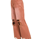 side view of Rust colored distressed knee jeans with raw hemline