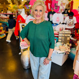 Dark green waffle knit top with boxy fit, raw seam, 3/4 sleeves, and longer back.