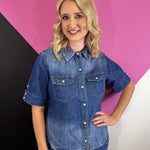 Medium wash denim button up top with snap front, collar, and chest pockets.