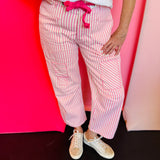 Pink striped twill barrel-leg pants with soft pink rope tie through silver eyelets and decorative front pockets; made from breathable 100% cotton for playful, standout style.