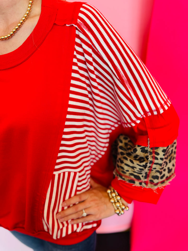 Close up of Red, stripe, and leopard oversized Dolman style long sleeve sweatshirt.