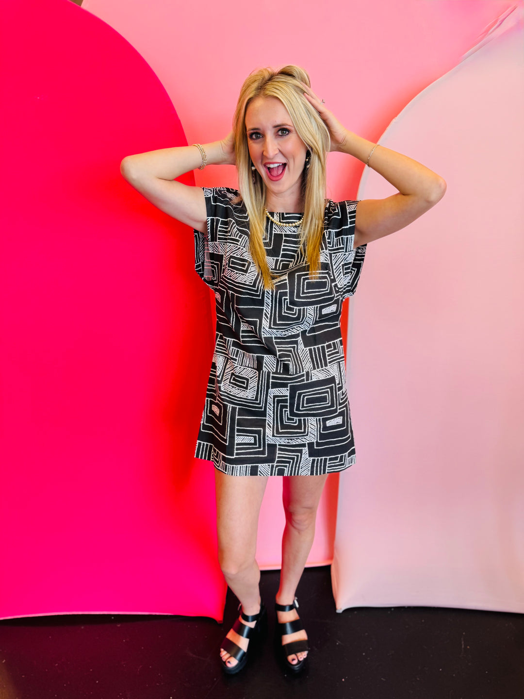 Black and white geometric print mini dress with structured shoulders and an open back.