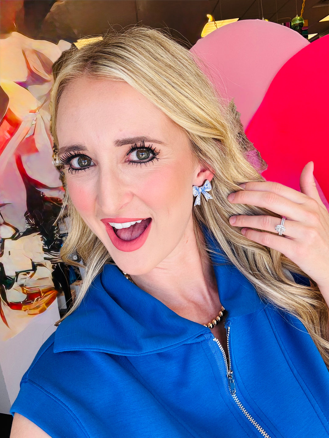 Woman showcasing the blue and white bow stud earrings made by Audra Style