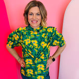 Green floral ruffle top with mock neckline and V-shaped layered ruffle detailing.