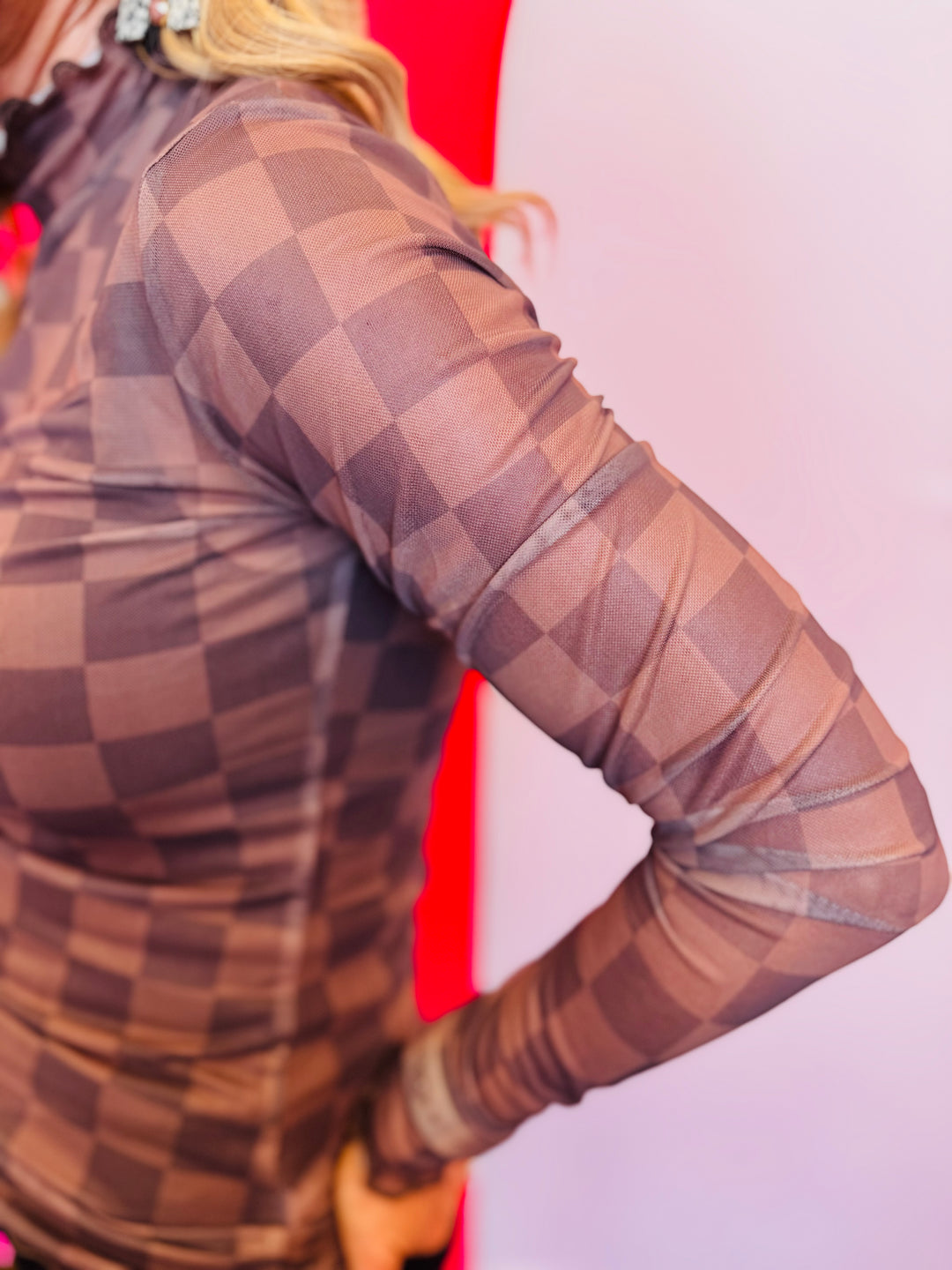 Sleeve view of the Keigan Mesh Top- chocolate checkered print, sheer mesh fabric, and lettuce-edge hems