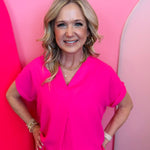 Fuchsia woven blouse with V-neckline and cuffed short sleeves.