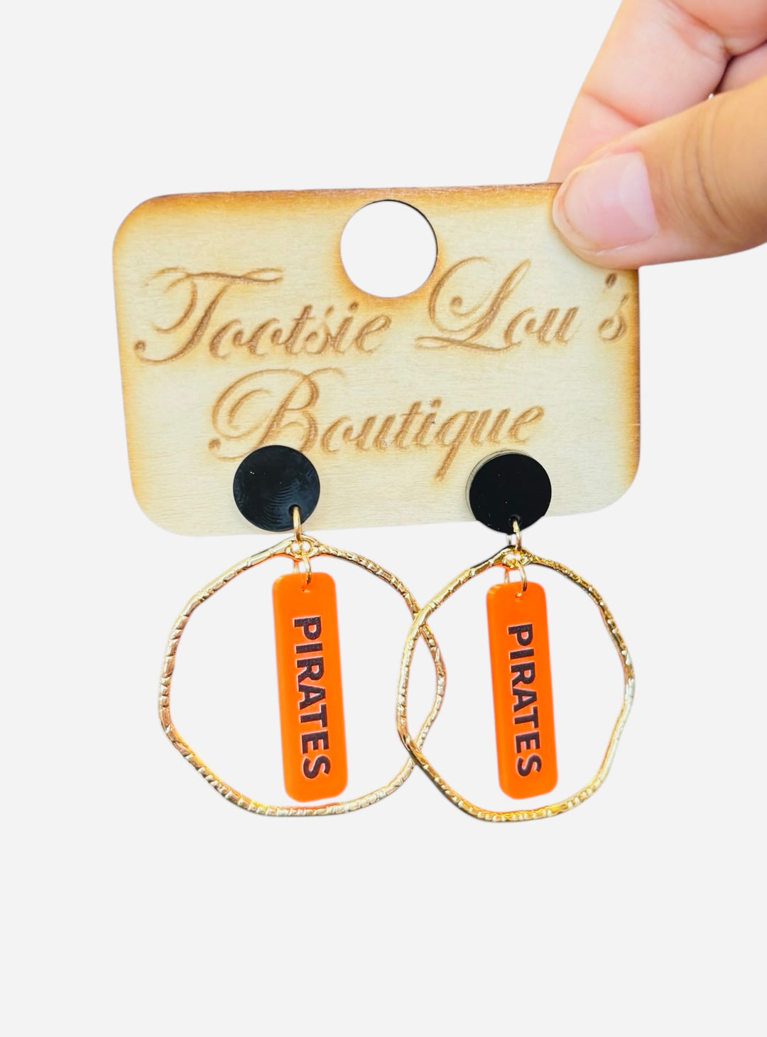 Gold hoops with orange dangle and black writing saying Pirates set on a black stud.