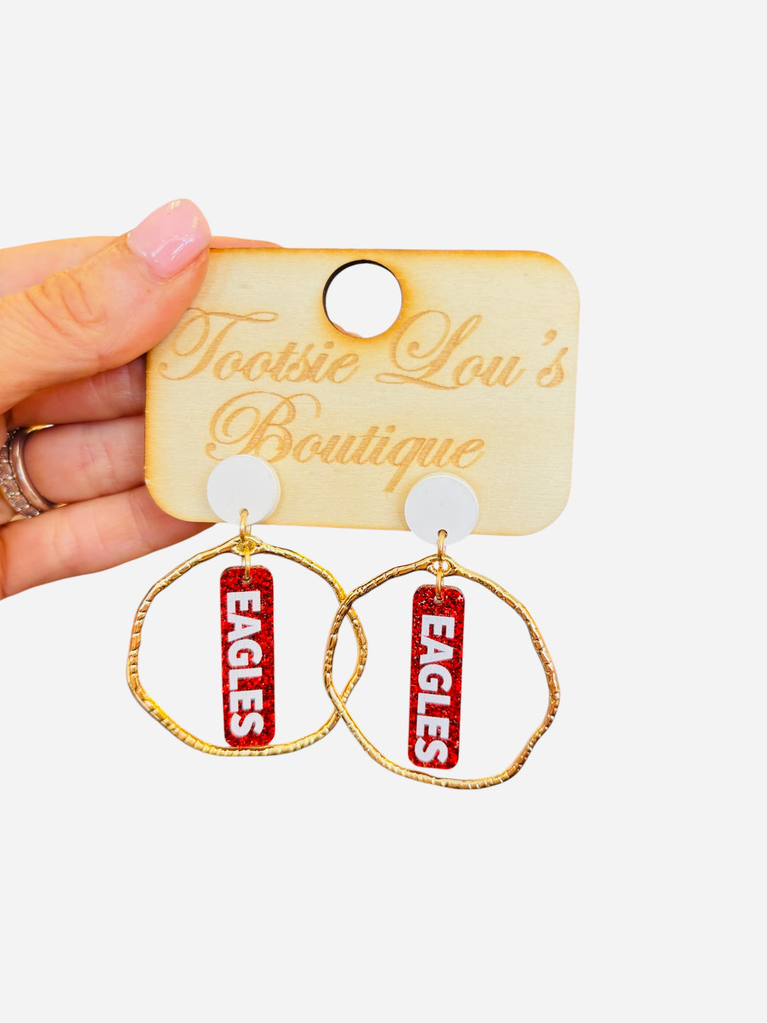 Gold hoops with red glitter dangles and white writing that says Eagles set on white stud.