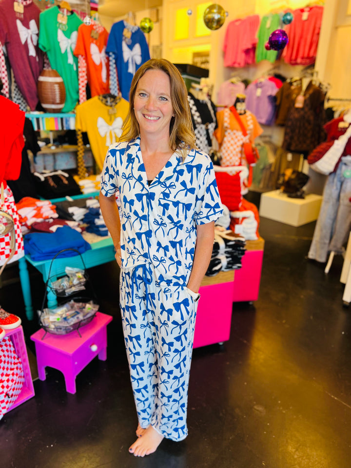 White pajama set with soft blue bow print, featuring a relaxed-fit short-sleeve top and matching pants made from lightweight, stretchy fabric for cozy comfort.