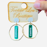 Gold hoops with mirrored green dangles and white writing that’s says Hawks set on white stud