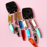Acrylic confetti dangle earrings with sparkling black tops and multicolor gold, green, red, and blue accents