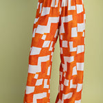 Orange and white geometric wide-leg pants with elastic drawstring waist in lightweight rayon-blend fabric.