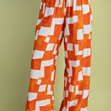 Orange and white geometric wide-leg pants with elastic drawstring waist in lightweight rayon-blend fabric.
