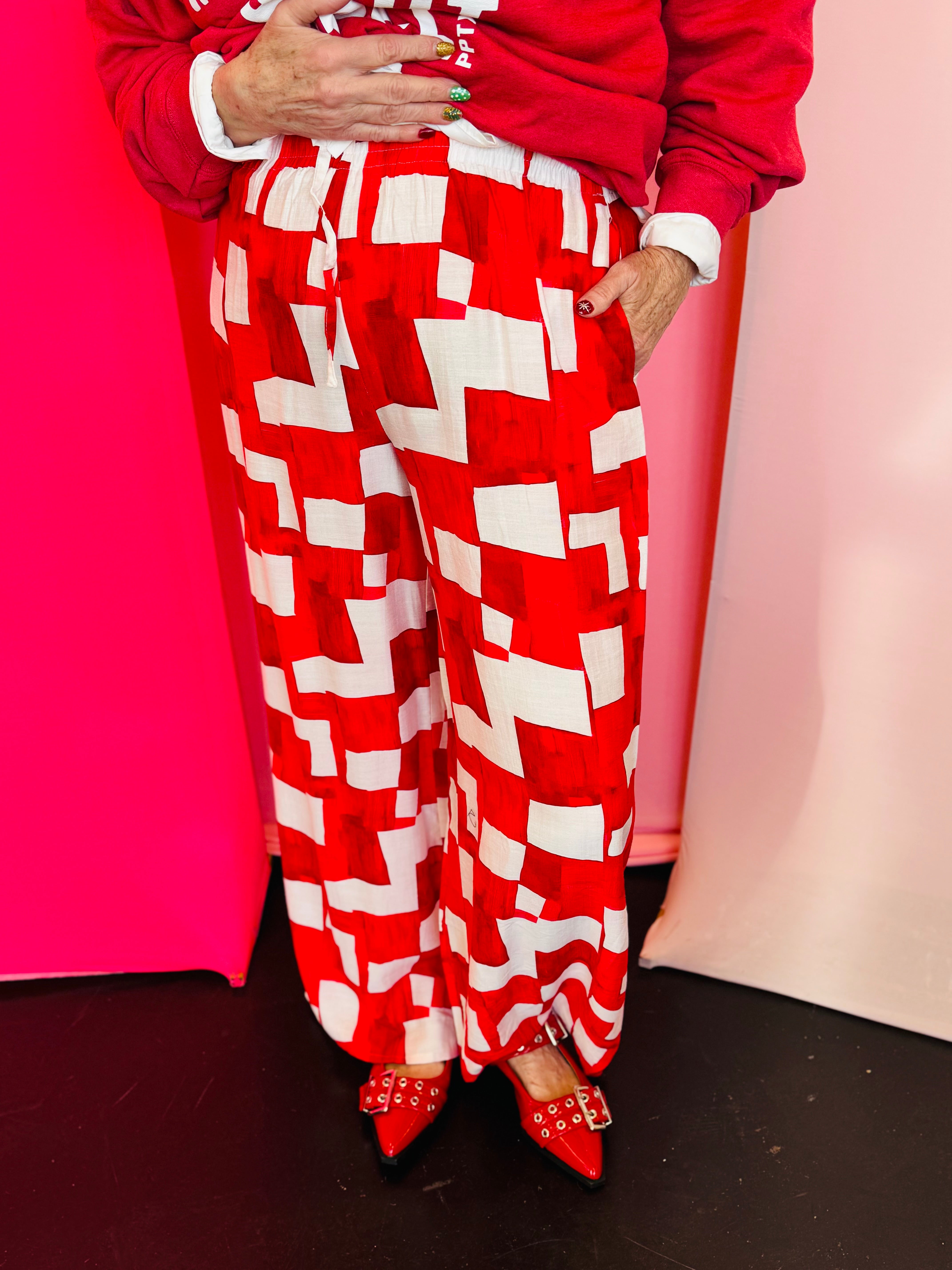 Red and white geometric wide-leg pants with elastic drawstring waist in lightweight rayon-blend fabric.