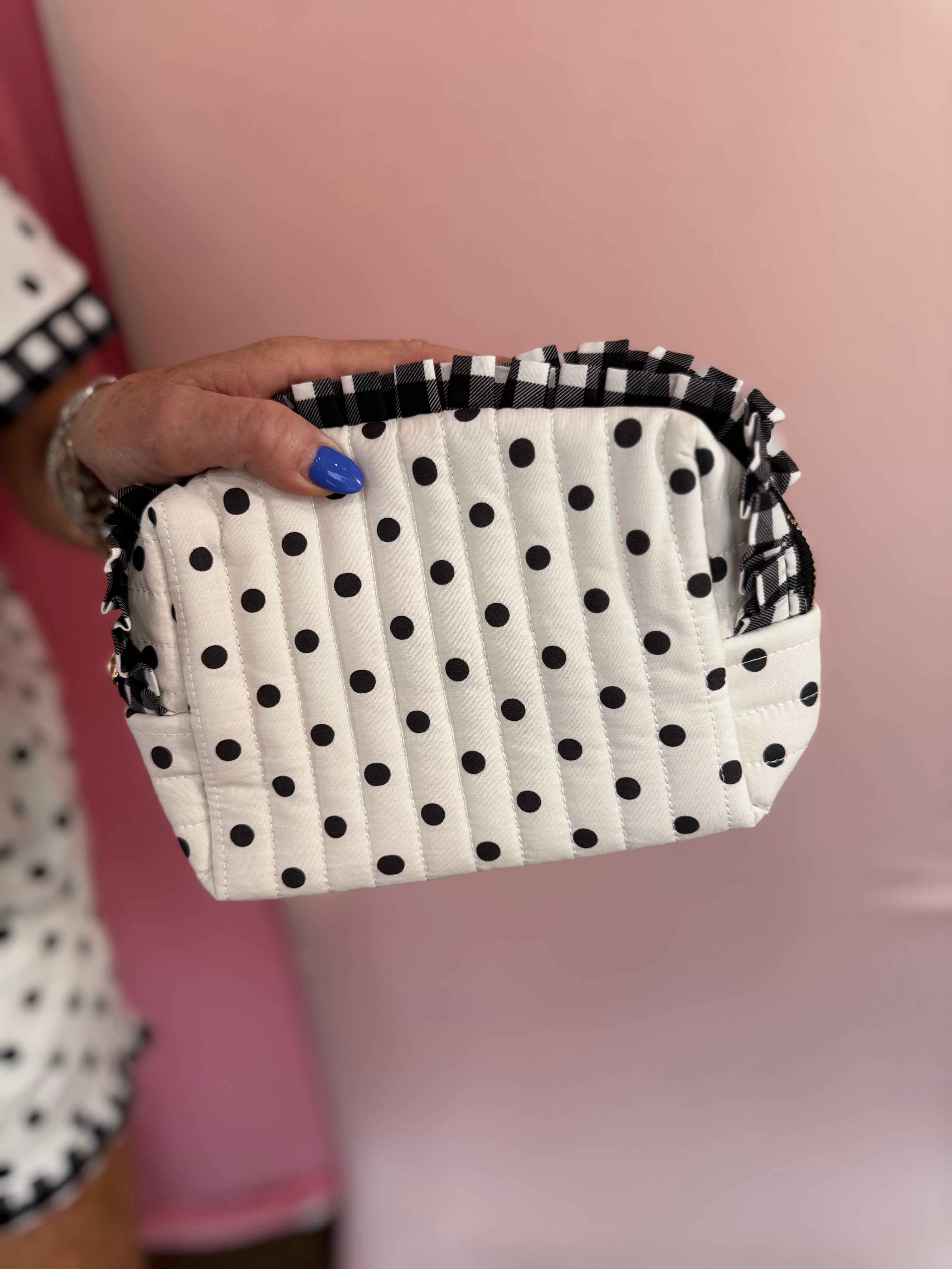 Black and white polka dot quilted bag with gingham ruffle trim and zipper closure.