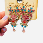 Rhinestone reindeer earrings with multicolor gems, fluttery lashes, red nose, and teardrop accent.