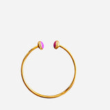 Gold cuff bracelet with purple circles on ends, surrounded by sparkling rhinestones for elegant shimmer.