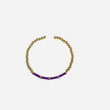 Semi-open bangle with gold round beads and curved front section of purple cylindrical segments.