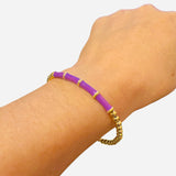 Waterproof gold bangle with purple cylindrical accents and round bead design for elegant modern style.