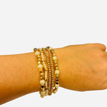 Set of five gold and pearl stretch bracelets with water-resistant finish and polished elegant shine.
