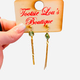 Asymmetrical gold earrings with olive stones, bar drop, and chain strands.