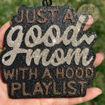 Black car freshie with gold and brown glitter text saying “Just A Good Mom With A Hood Playlist.”