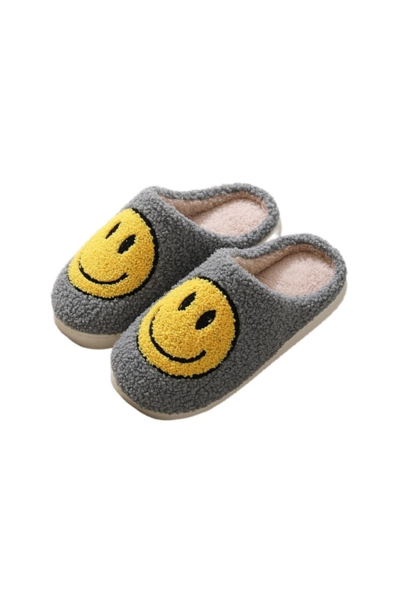 Gray plush slippers with oversized yellow smiley face, soft and cozy for indoor lounging.