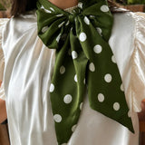 Green and white silky polka dot scarf with versatile styling options.