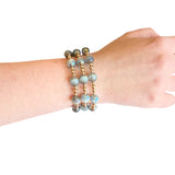 Water resistant grey beaded elastic bracelet with pearlescent beads and gold spacer accents.