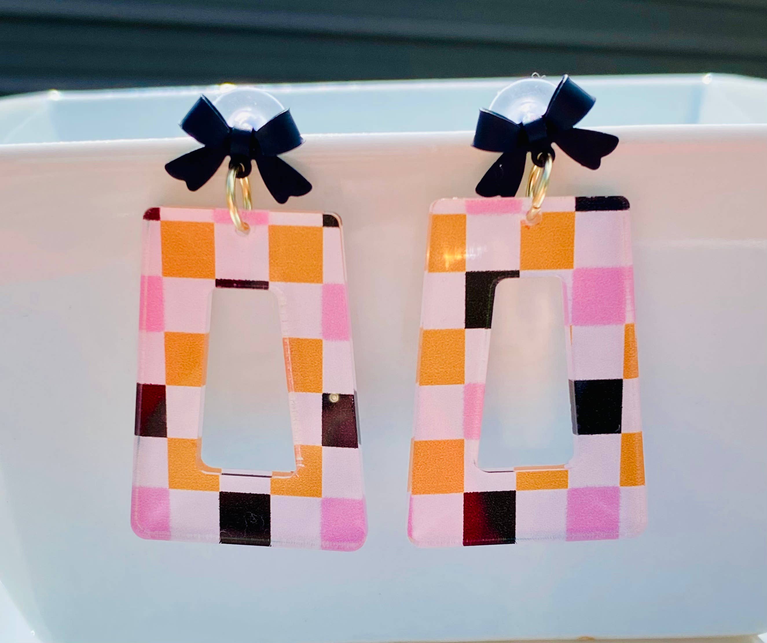 Halloween checkered acrylic earrings with black bow studs and geometric cutout design.