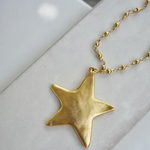 Hammered gold star pendant necklace on sleek gold chain with subtle textured shine.