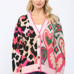 Oversized cardigan with heart, leopard, and mixed patterns in pink, green, beige, and black.