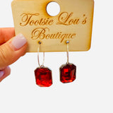 Gold hoop earrings with dangling ruby red emerald-cut stones.