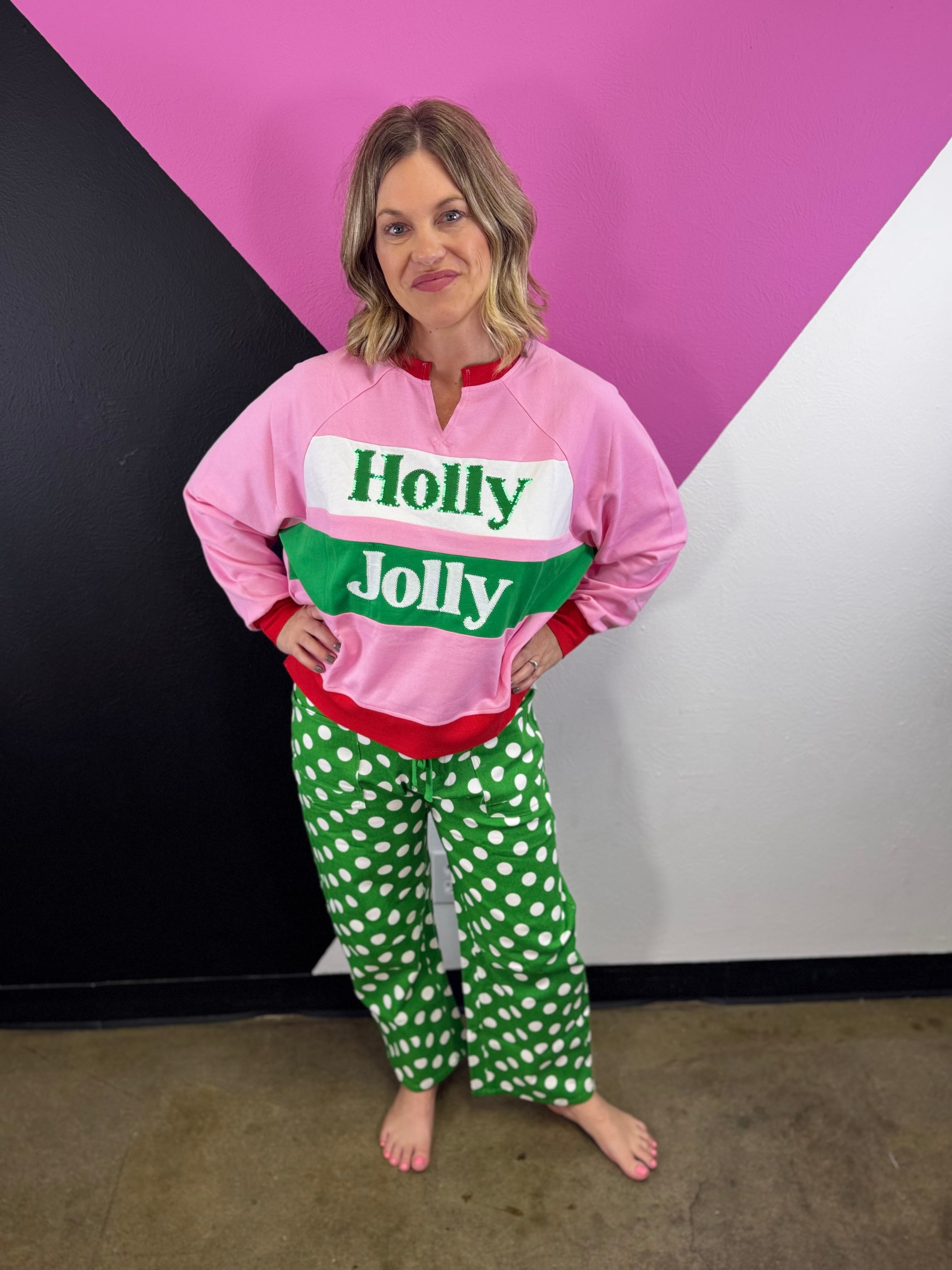 Pink green red and white Holly Jolly pullover with bold lettering and red trim.