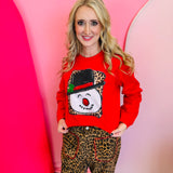 Red snowman sweatshirt with leopard print background and holly-trimmed black hat