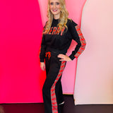 Black “Merry” sweat set with red plaid lettering and matching plaid jogger stripes.